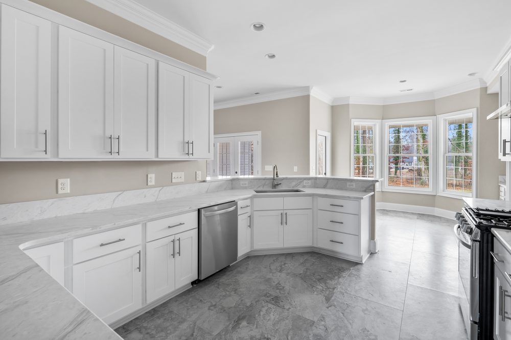 White shaker kitchen with an L-shaped run, peninsula sink, marble-look counters and stainless dishwasher
