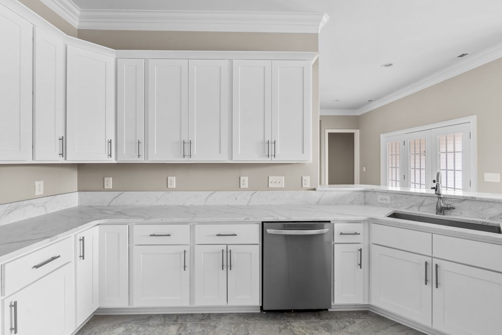 White shaker cabinets along a sink run with a pass-through opening to the next room